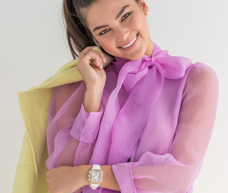 Young woman wearing fashionable and colorful top with the Deco watch featuring a rainbow of sparkling topaz stones along the bezel and bright white leather strap.